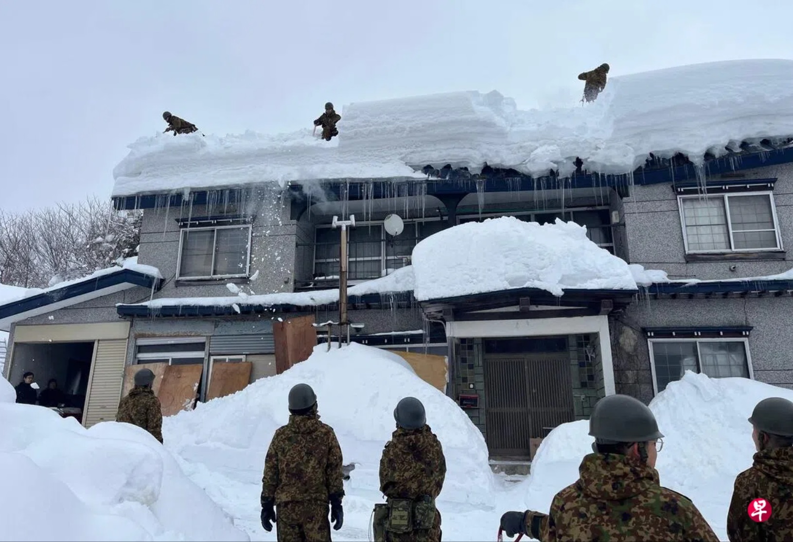 日本自卫队成员星期二在青森市协助居民清理屋顶上的积雪